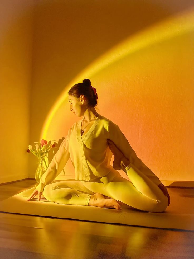 Woman practicing a gentle seated pigeon pose variation on a Healing Factor EVA mat, showing comfort and warmth in a cozy, golden-hour setting.