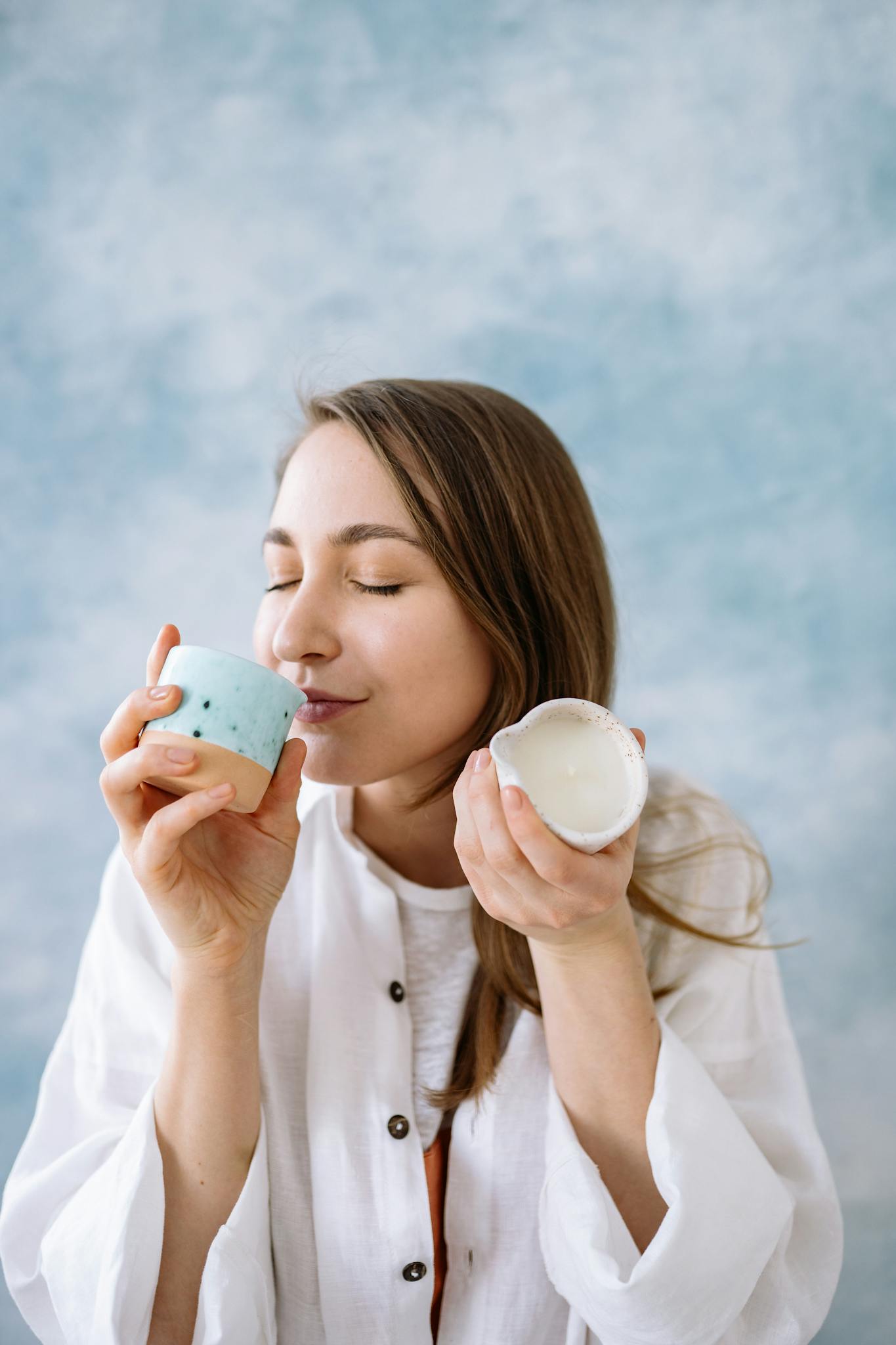 Woman in white blouse enjoying the scent of aromatic candles, creating a serene and fragrant ambiance.